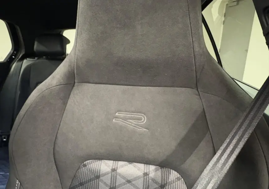 Gros plan sur le siège avant en alcantara noir avec logo R, ceinture de sécurité visible à droite.