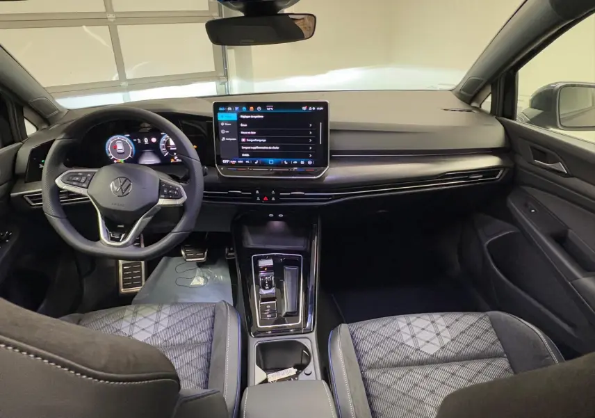 Vue intérieure avant de la Volkswagen Golf 2.0 TDI 150 DSG7 R-Line avec tableau de bord moderne et sièges tissu noir.