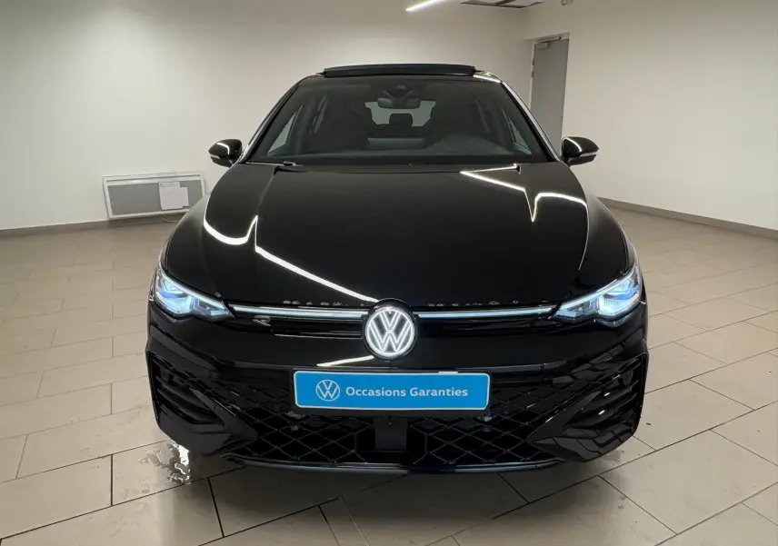 Vue frontale d'une Volkswagen Golf 2.0 TDI 150 DSG7 R-Line noire Grenadille avec phares LED allumés en intérieur.