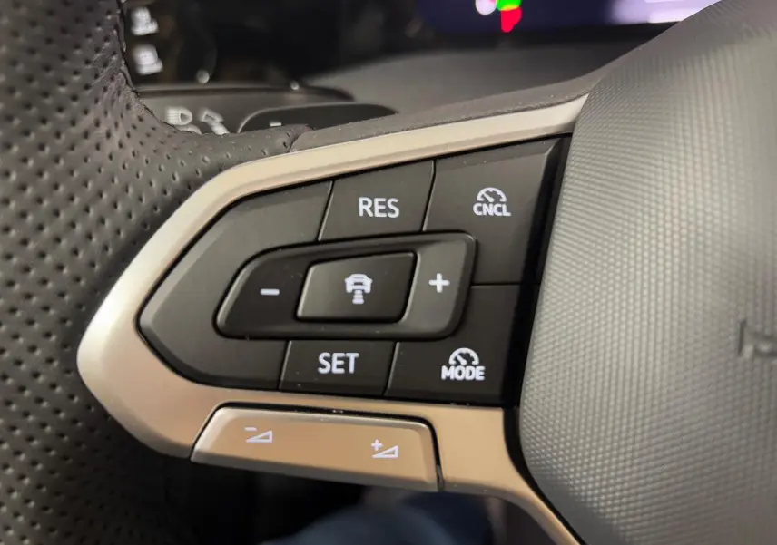 Gros plan sur les commandes de régulateur de vitesse au volant cuir perforé de la Volkswagen Golf 2.0 TDI noir grenadille.