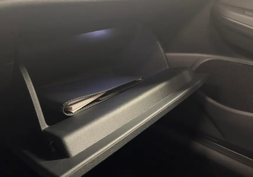 Gros plan sur la boîte à gants ouverte de la Volkswagen Golf 2.0 TDI 150 DSG7 R-Line noir Grenadille, intérieur sombre.