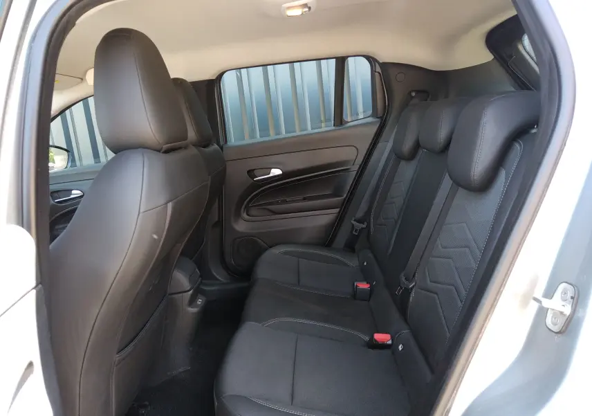Vue intérieure côté droit montrant la banquette arrière noire du Jeep Avenger eHYBRID 2025 avec appuie-têtes et ceintures.