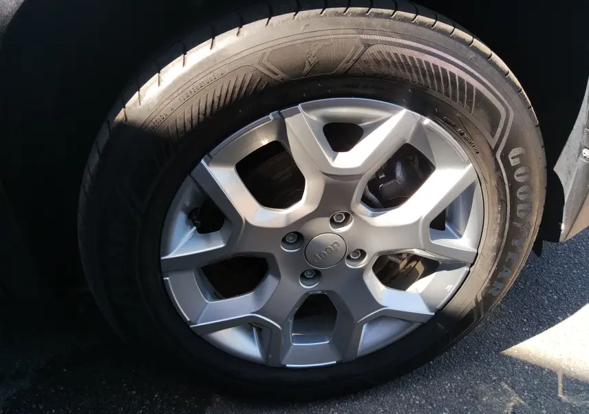 Gros plan sur la jante argentée de la Jeep Avenger eHYBRID 110ch, avec pneu Goodyear visible en lumière naturelle.