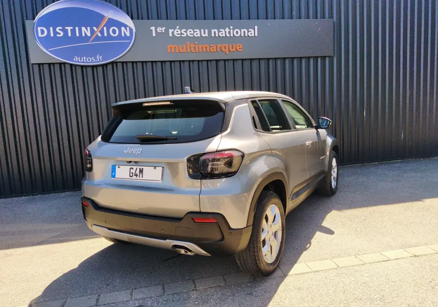 Jeep Avenger gris en 3/4 arrière droit, mettant en valeur ses feux arrière fumés et ses jantes blanches.