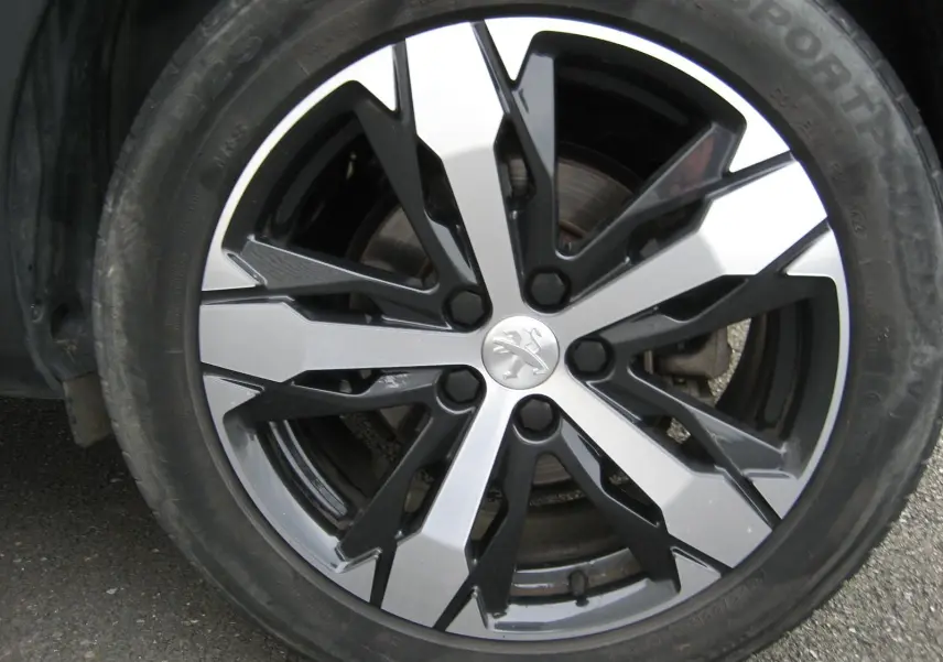 Gros plan sur la jante bicolore noire et argentée du Peugeot 3008 Business 2020 avec logo lion au centre.