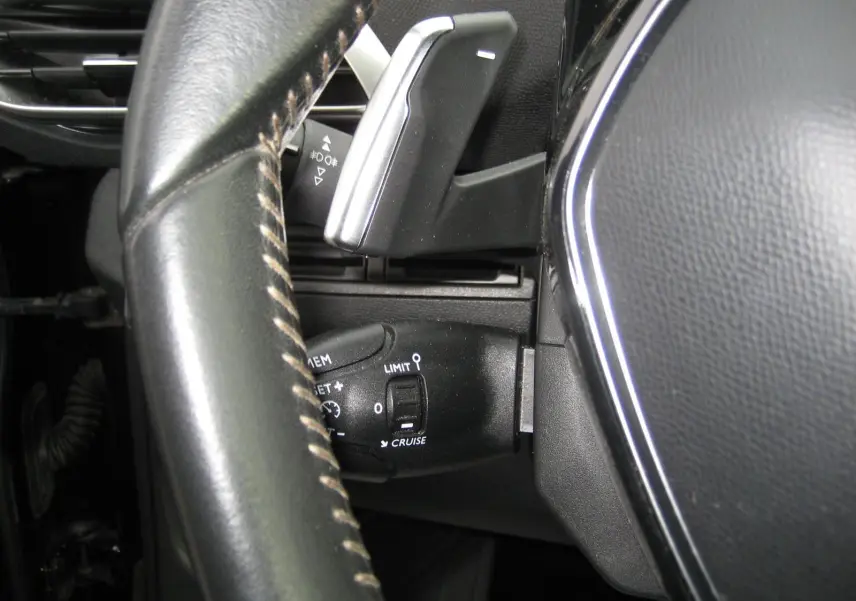 Gros plan sur la commande de régulateur de vitesse et levier de vitesses au volant du Peugeot 3008 noir Business 2020.