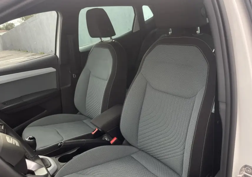 Intérieur de la SEAT IBIZA 2025, vue côté droit sur les sièges avant gris avec coutures blanches et volant multifonction.