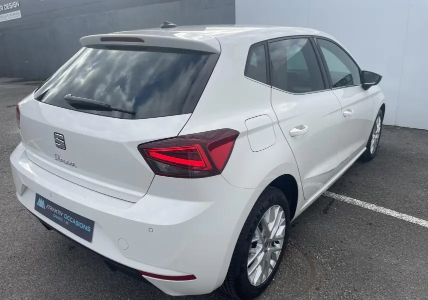 Vue 3/4 arrière droite d'une SEAT Ibiza blanche avec feux arrière LED en triangle et jantes alliage 16 pouces.