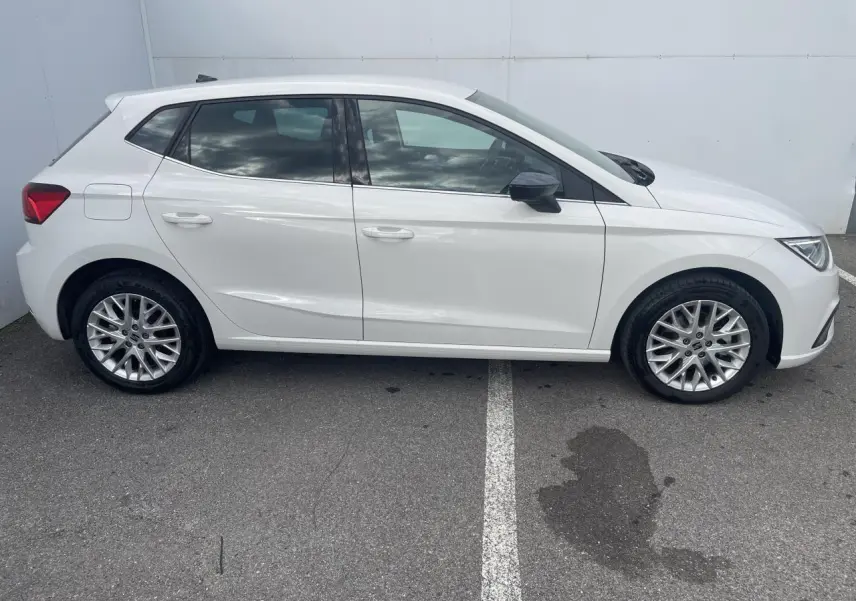 Profil côté gauche d'une SEAT IBIZA blanche 2025 avec jantes alliage et vitres teintées arrière sur parking.