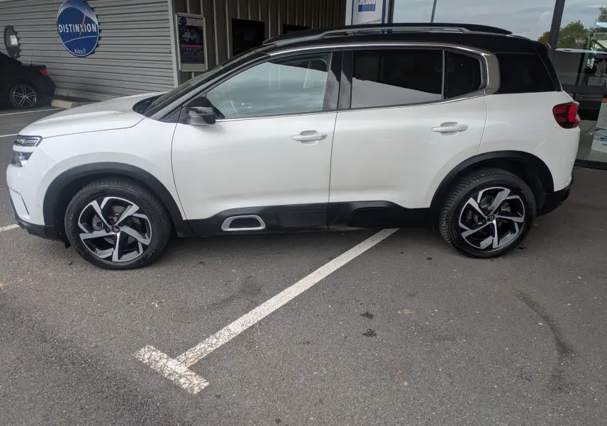 Vue de profil côté gauche d'un Citroën C5 Aircross blanc 2020 avec toit noir et jantes alliage bicolores.