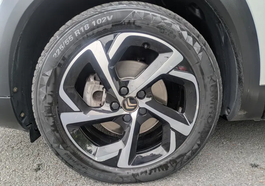 Gros plan sur la roue avant droite d’un Citroën C5 Aircross blanc, mettant en valeur la jante bi-ton noire et argent.
