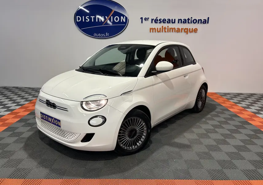 Vue 3/4 avant droite d'une Fiat 500 électrique blanche avec jantes spécifiques et logo noir sur calandre.