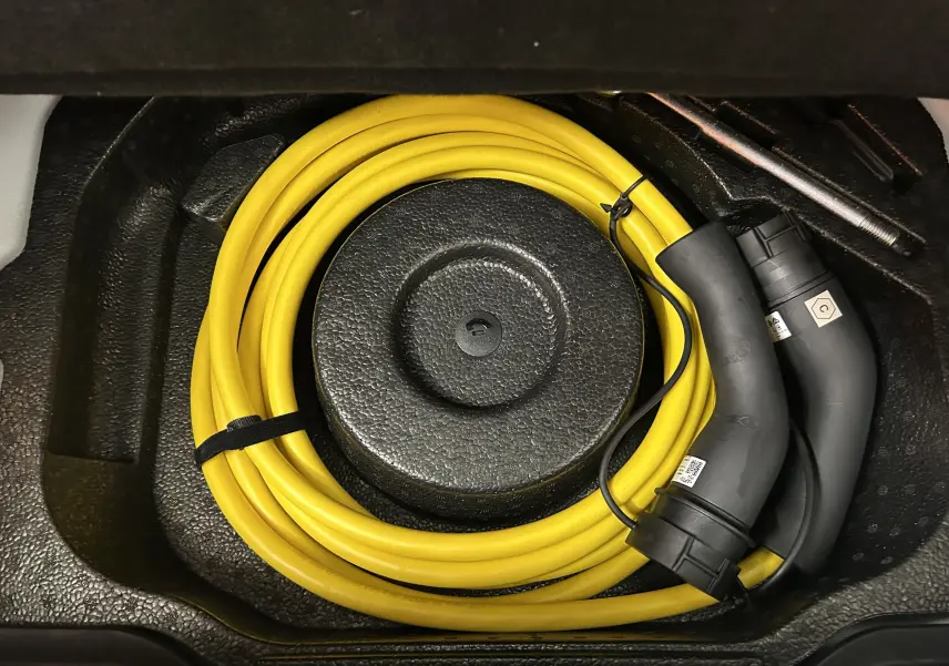Câble de recharge électrique jaune enroulé dans le coffre d'une Fiat 500 électrique 2023, vue de dessus.