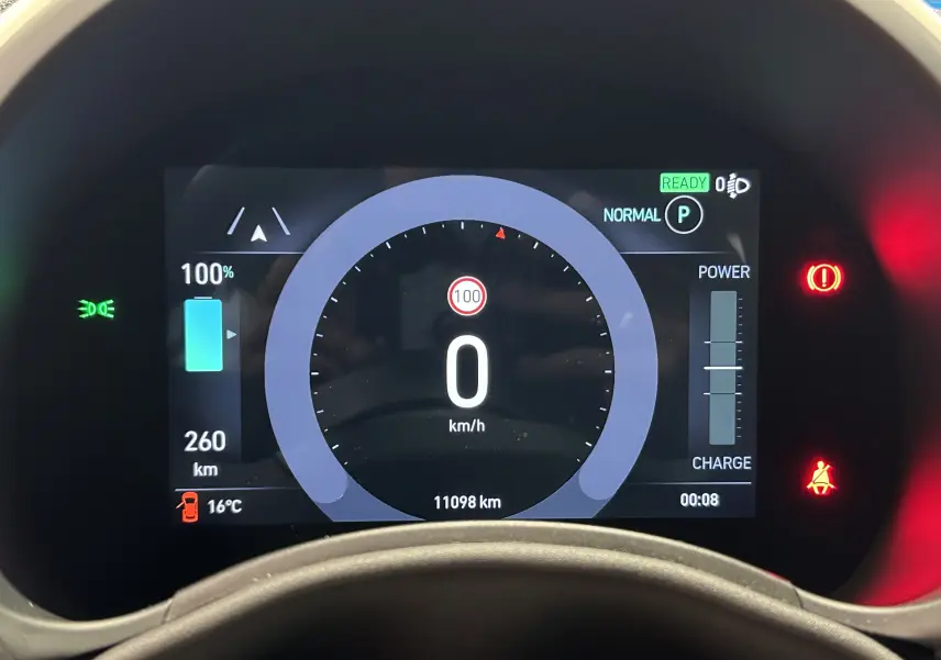 Affichage numérique du tableau de bord de la Fiat 500 électrique 2023, montrant la batterie à 100% et la vitesse à 0 km/h.