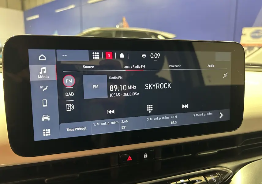 Écran tactile central de la FIAT 500 électrique 2023 affichant la radio FM sur Skyrock, vue intérieure frontale.