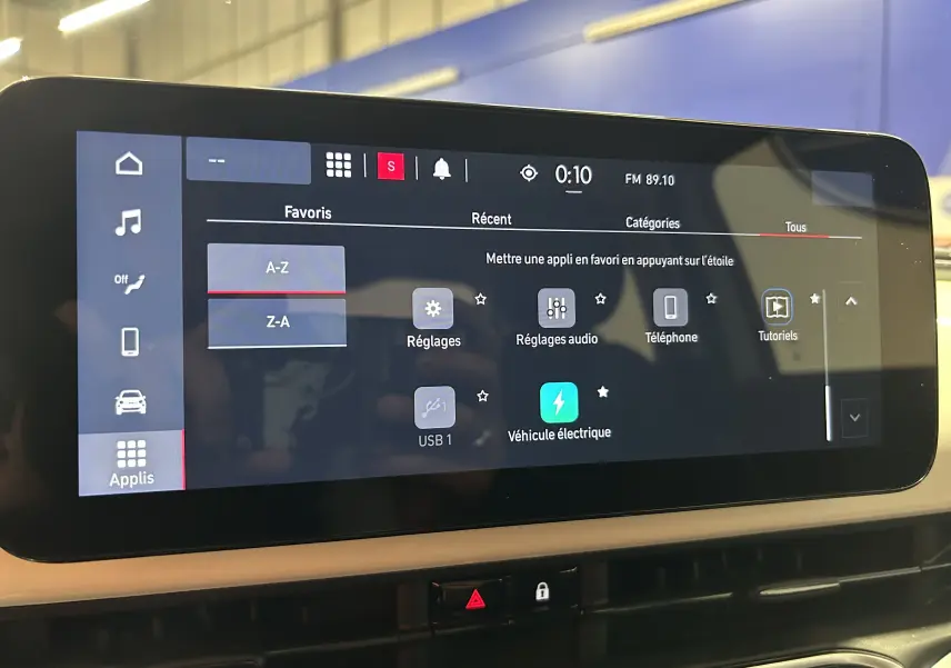 Écran tactile central de la Fiat 500 électrique 2023 affichant le menu des applications avec icône véhicule électrique.