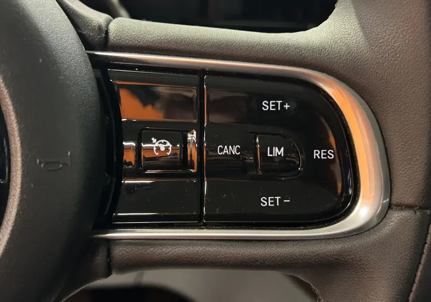Gros plan sur les commandes de régulateur de vitesse à droite du volant d’une FIAT 500 électrique blanche.