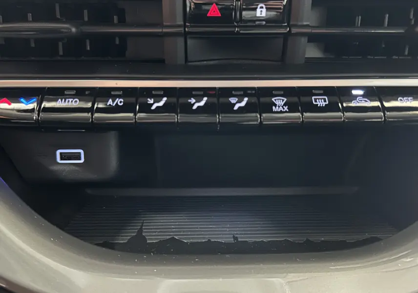 Gros plan sur la console centrale de la Fiat 500 électrique blanche, montrant les commandes de climatisation et un port USB.