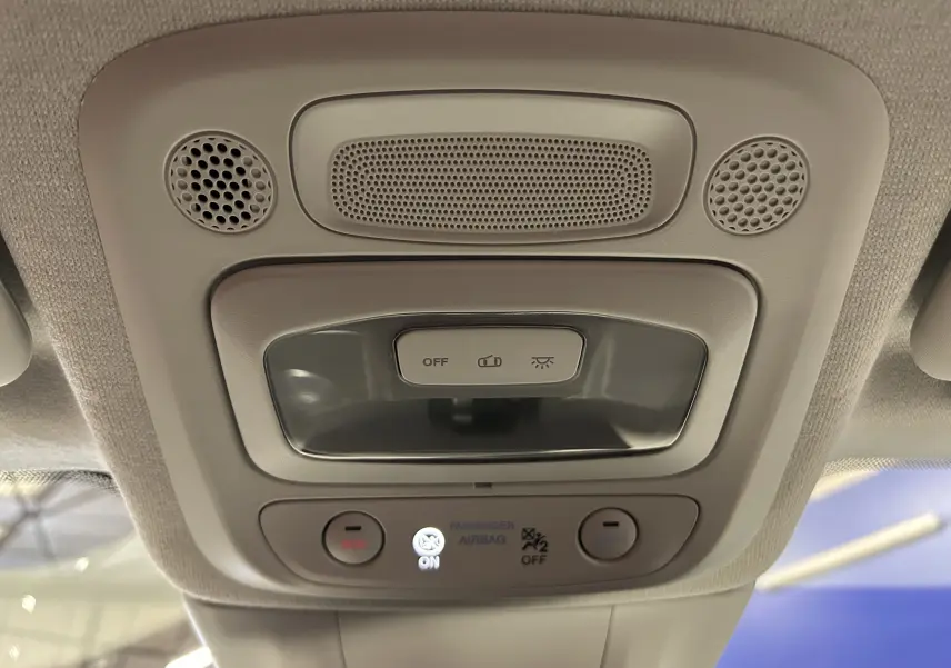 Plafonnier intérieur avec commandes d’éclairage et indicateurs de sécurité dans une Fiat 500 électrique blanche, vue en contre-plongée.