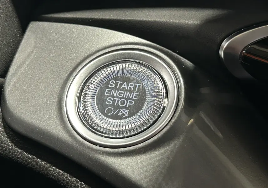 Gros plan sur le bouton Start Engine Stop du tableau de bord noir de la FIAT 500 électrique blanche 2023.