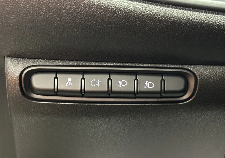Gros plan sur les boutons de contrôle d’éclairage et d’aide à la conduite dans une Fiat 500 électrique blanche de 2023.
