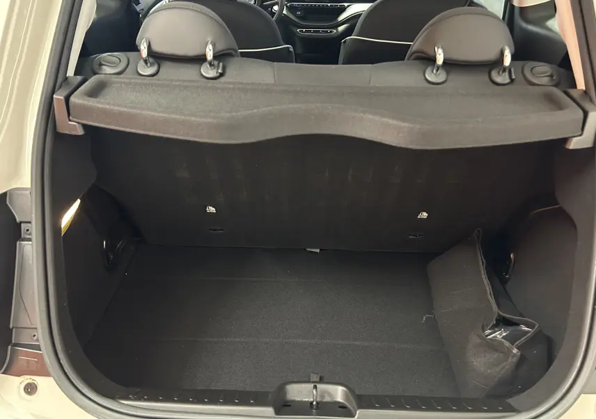 Coffre ouvert vu de l'arrière d'une FIAT 500 électrique blanche, montrant l'espace de chargement et les appuis-tête noirs.
