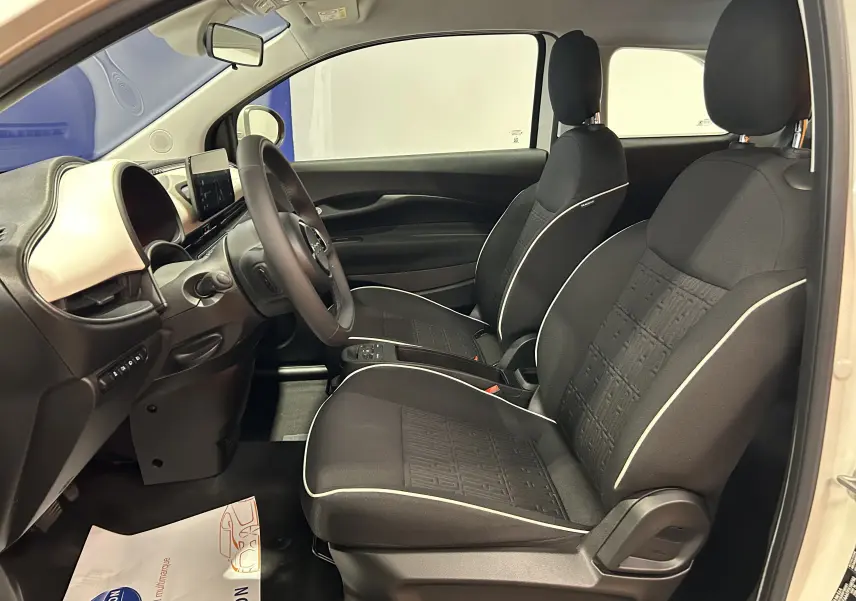 Intérieur de la Fiat 500 électrique 2023 vue côté droit, sièges noirs avec surpiqûres blanches et tableau de bord clair.