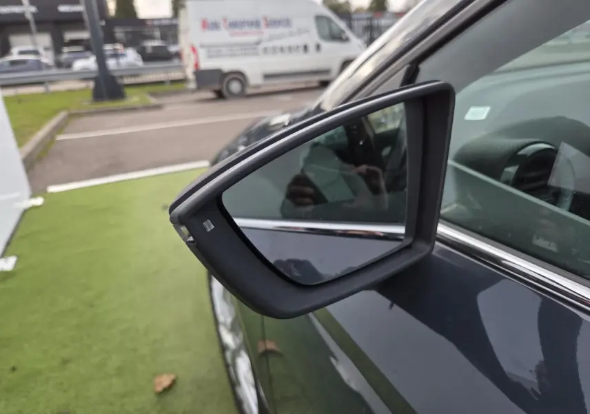 Rétroviseur côté gauche en gros plan sur SEAT Ibiza 2025 bleu Fjord métallisé stationnée sur pelouse artificielle.