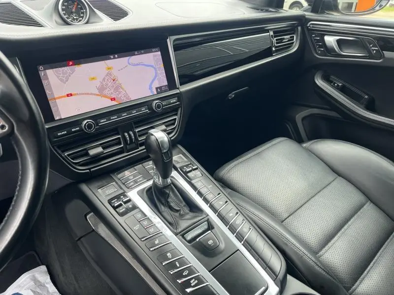 Intérieur noir du Porsche Macan 2018 vu côté passager, avec console centrale et écran tactile GPS allumé.
