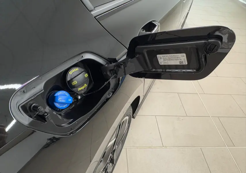 Vue rapprochée de la trappe à carburant ouverte côté gauche d'une Volkswagen Golf noire Grenadille avec bouchons Diesel et AdBlue visibles.