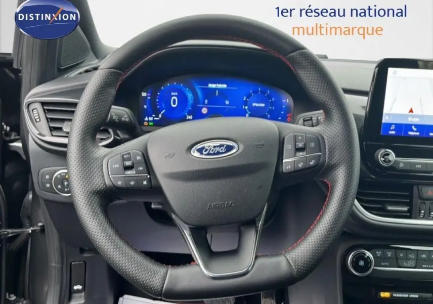 Vue intérieure centrée sur le volant perforé de la Ford Puma 2024 avec tableau de bord numérique et écran tactile GPS.