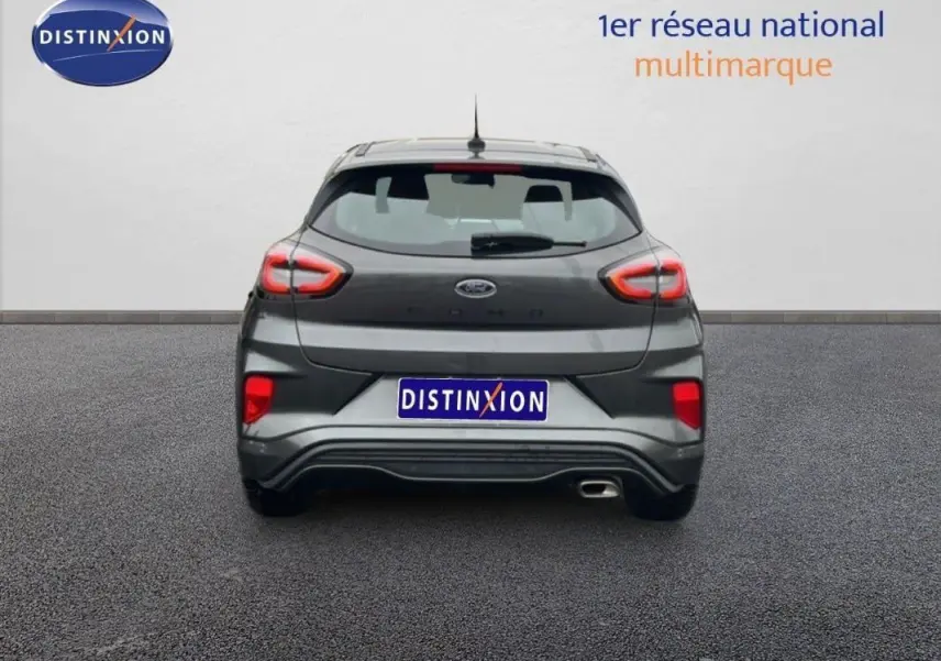 Vue arrière d'une Ford Puma gris foncé 2024 avec feux arrière allumés et échappement visible côté droit.