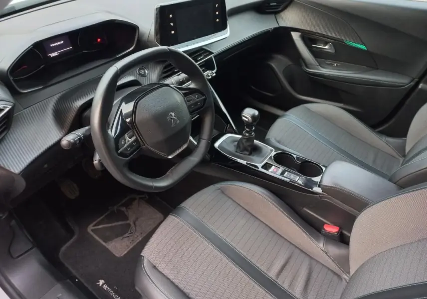 Intérieur avant droit de Peugeot 2008 blanc 2021, volant compact, écran tactile et levier de vitesse manuel visibles.
