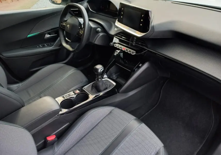 Vue intérieure côté conducteur du Peugeot 2008 blanc de 2021, avec tableau de bord moderne et boîte manuelle.