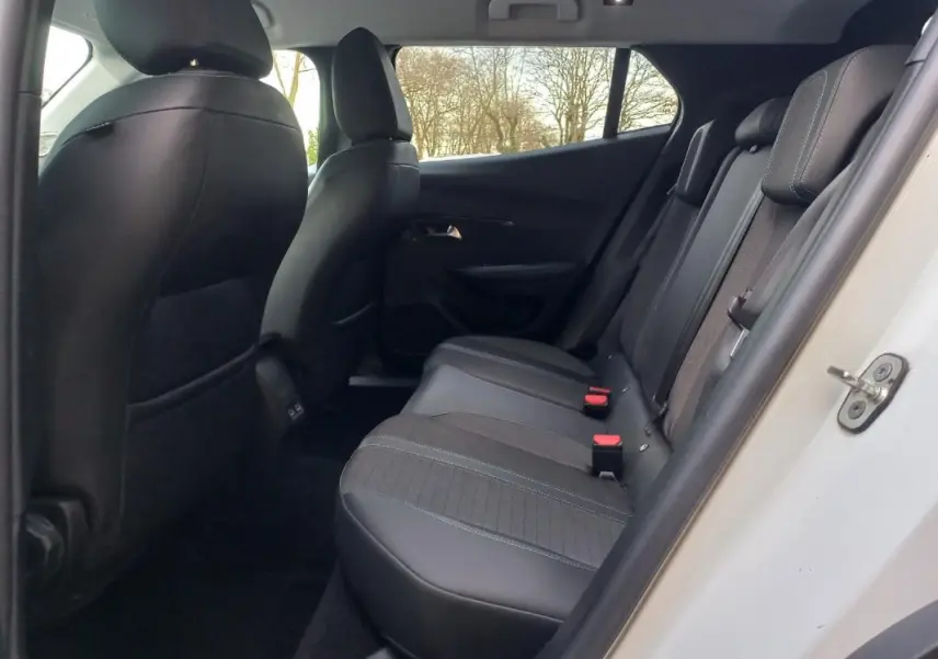 Vue intérieure côté arrière droit du Peugeot 2008 blanc, montrant les sièges arrière en tissu et cuir noir.