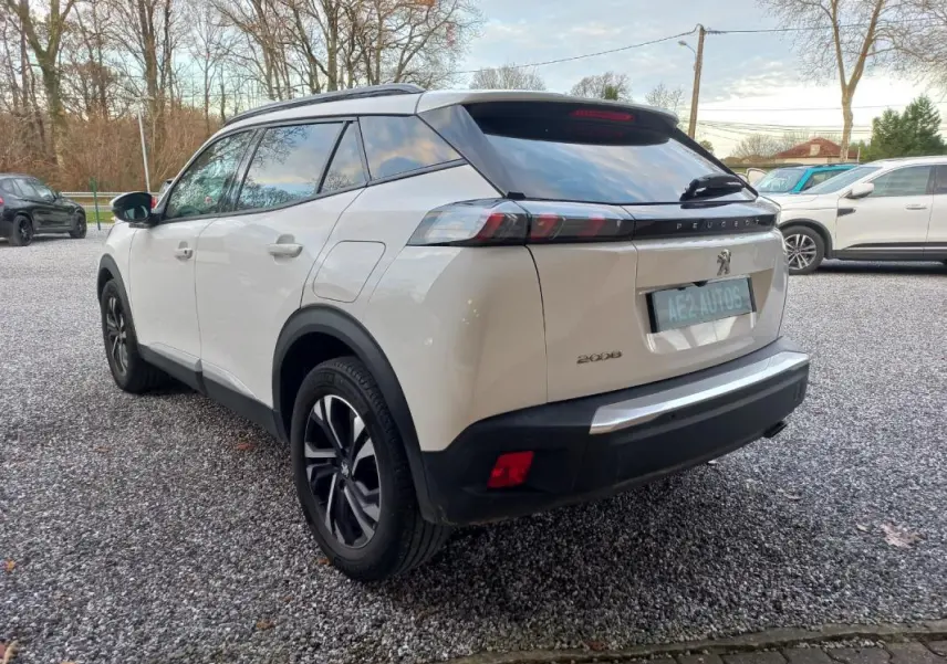 Peugeot 2008 blanc vue 3/4 arrière droit, jantes alliage noires, vitres teintées et toit noir contrasté.