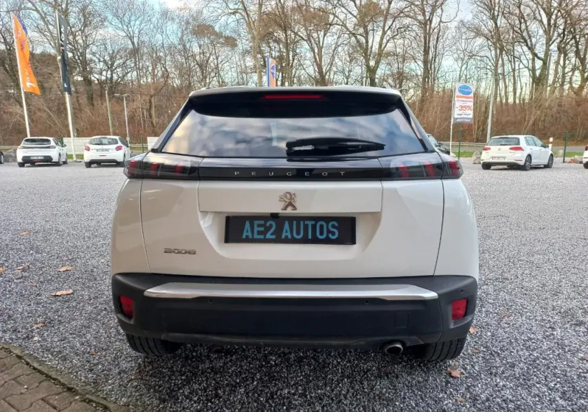 Vue arrière d'un Peugeot 2008 blanc de 2021 avec feux arrière noirs et plaque AE2 AUTOS visible.