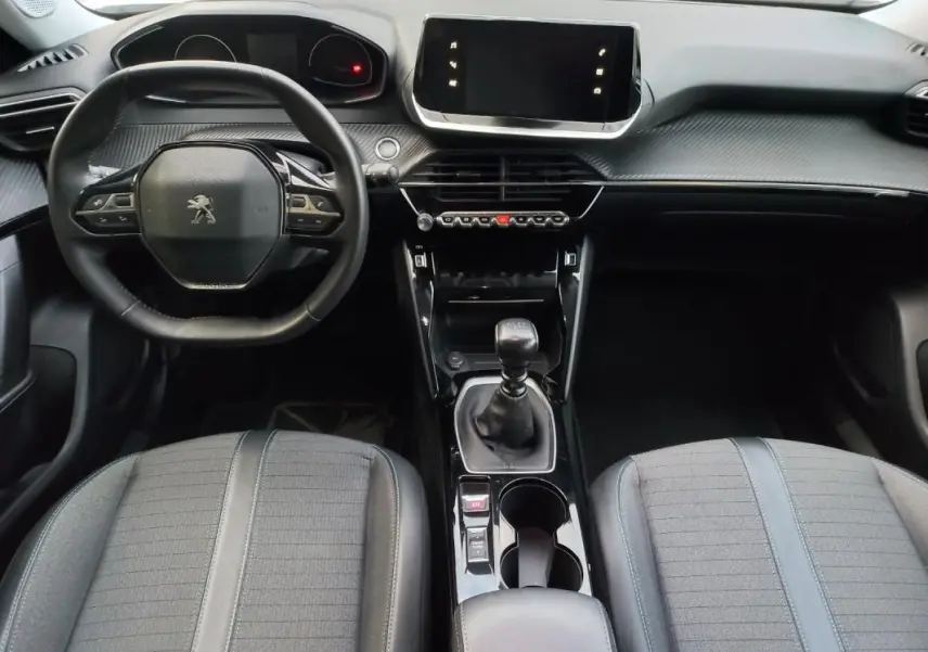 Vue intérieure avant du Peugeot 2008 blanc 2021, tableau de bord moderne avec écran tactile et boîte manuelle.