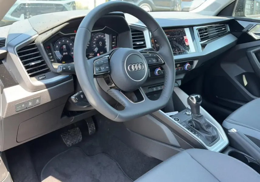 Intérieur de l'Audi A1 Sportback 30 TFSI 2026, vue côté conducteur sur le volant cuir et la console centrale.