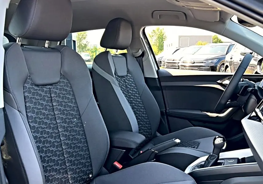 Vue intérieure côté droit de l’Audi A1 Sportback 2026, sièges sport noirs avec motifs géométriques et accoudoir central.