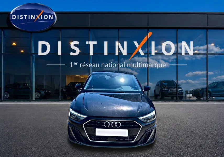 Audi A1 Sportback noir vue de face, stationnée devant une vitrine avec logo Distinxion en arrière-plan.