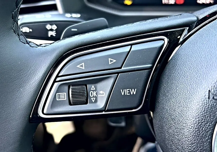 Gros plan sur les commandes multifonctions noires à gauche du volant cuir d’un Audi A1 Sportback 30 TFSI 2026.