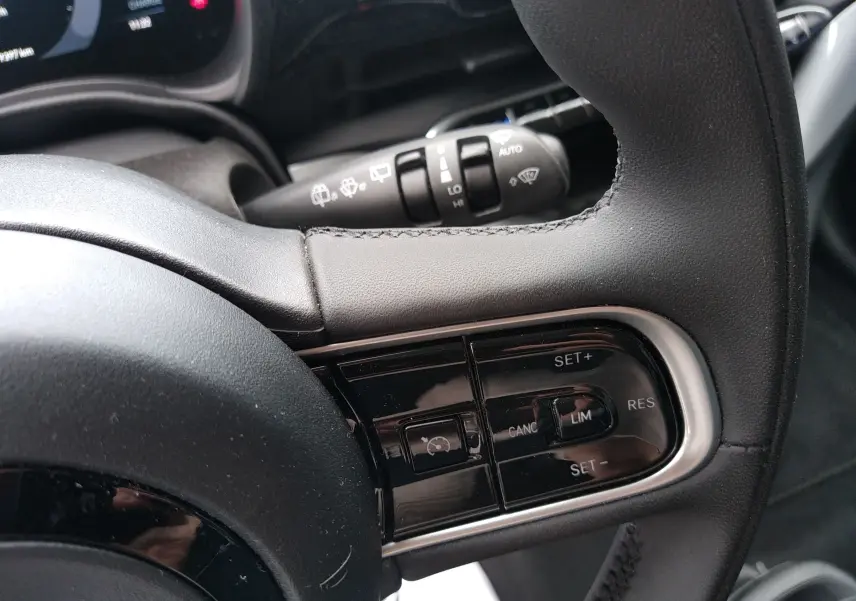 Gros plan sur le volant noir de la Fiat 500 électrique 2024, avec commandes de régulateur de vitesse intégrées.
