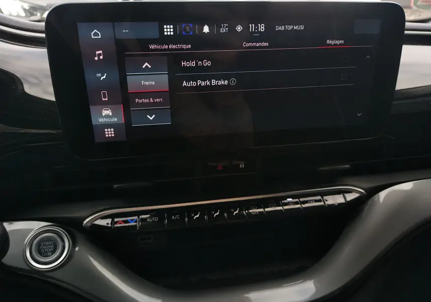 Écran tactile central de la Fiat 500 électrique 2024, vue intérieure du tableau de bord avec commandes climatisation et bouton start/stop.