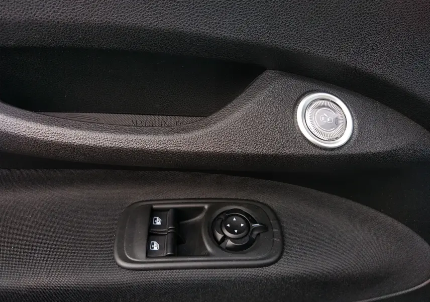 Détail intérieur côté gauche de la porte noire de la Fiat 500 électrique 2024 avec commandes de vitres et rétroviseurs.