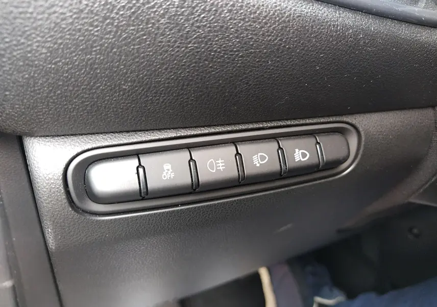 Gros plan sur les boutons de commande d’éclairage et d’aide à la conduite dans une Fiat 500 électrique noire de 2024.