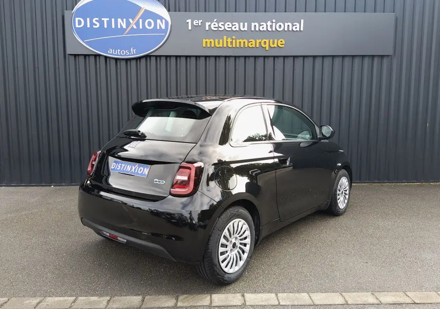 Vue 3/4 arrière droite d'une Fiat 500 électrique noire 2024 avec jantes blanches et feux arrière LED.