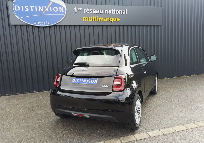 Vue 3/4 arrière droite d'une FIAT 500 électrique noire 2024, avec feux arrière LED et jantes blanches visibles.
