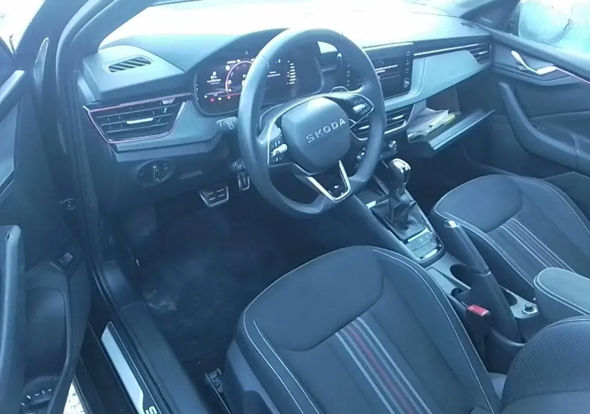Vue intérieure côté conducteur de la Skoda Scala Monte-Carlo 2025, sellerie noire avec bandes rouges et volant multifonctions cuir.