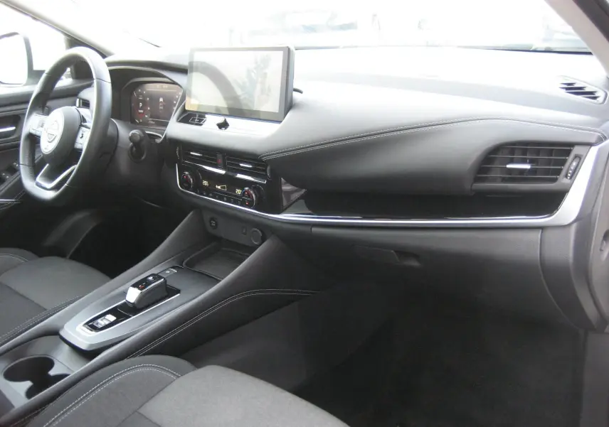 Intérieur du Nissan Qashqai III E-POWER 2024 vu côté passager, avec tableau de bord noir et écran tactile central.